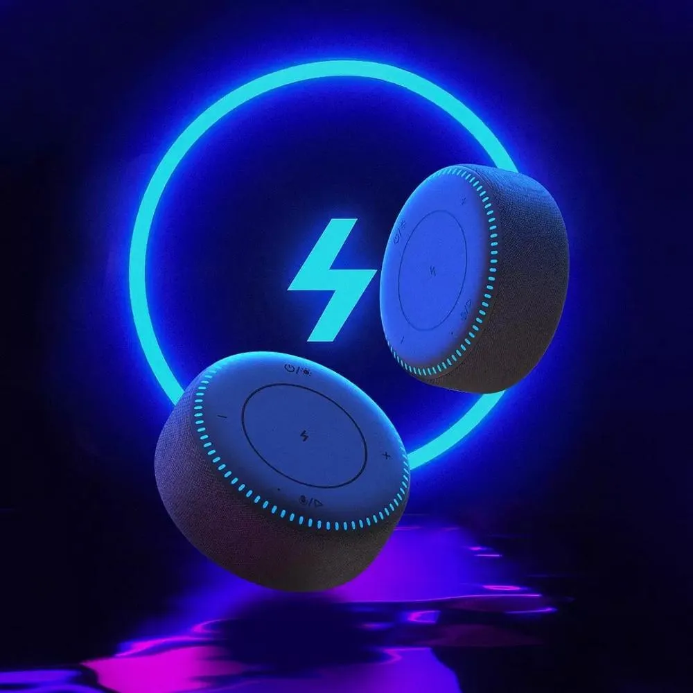 Black wireless charging Bluetooth speaker unit with USB port on a desktop.