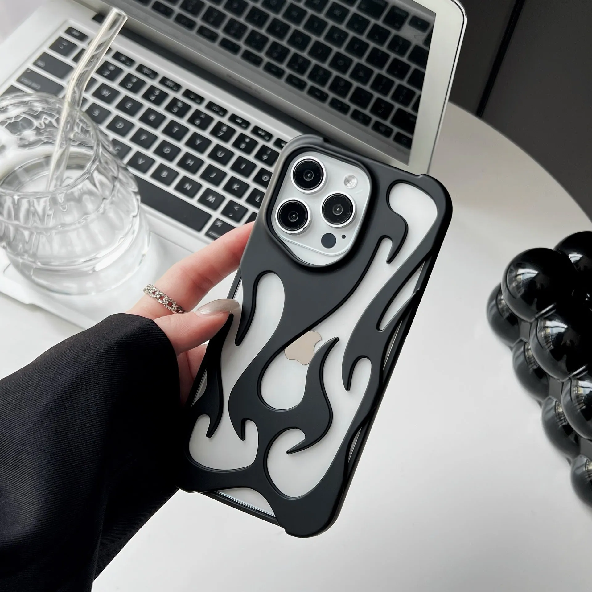 Electroplated hollow flame pattern TPU phone case for iPhone on a table, showing silver metallic finish and ventilation design.