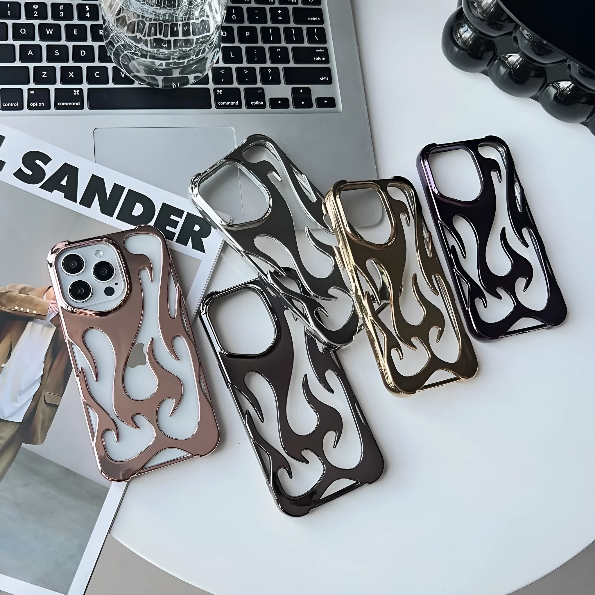 Electroplated hollow flame pattern TPU phone case for iPhone on a table, showing silver metallic finish and ventilation design.