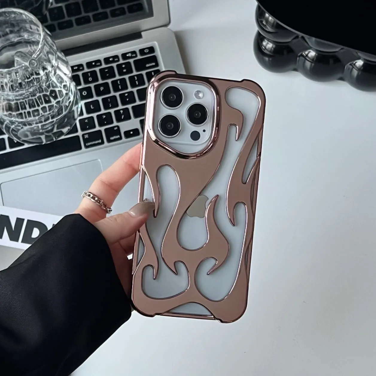 Electroplated hollow flame pattern TPU phone case for iPhone on a table, showing silver metallic finish and ventilation design.