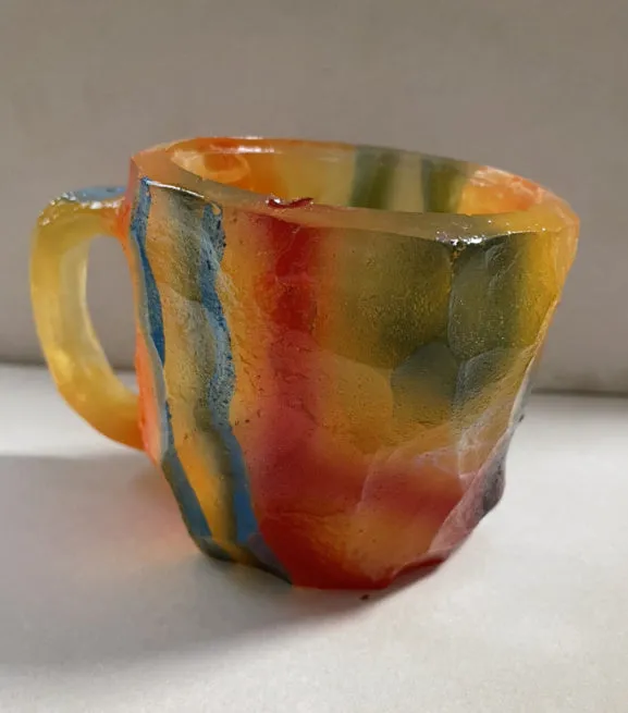 A purple resin coffee mug with a handle, showing a crystal-like structure, on a table.