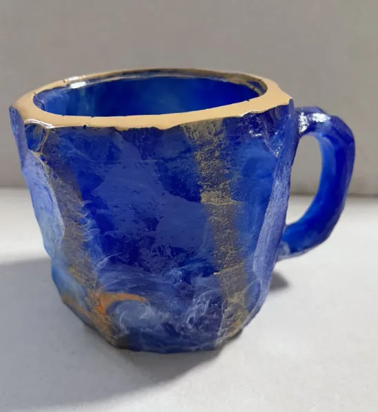 A purple resin coffee mug with a handle, showing a crystal-like structure, on a table.