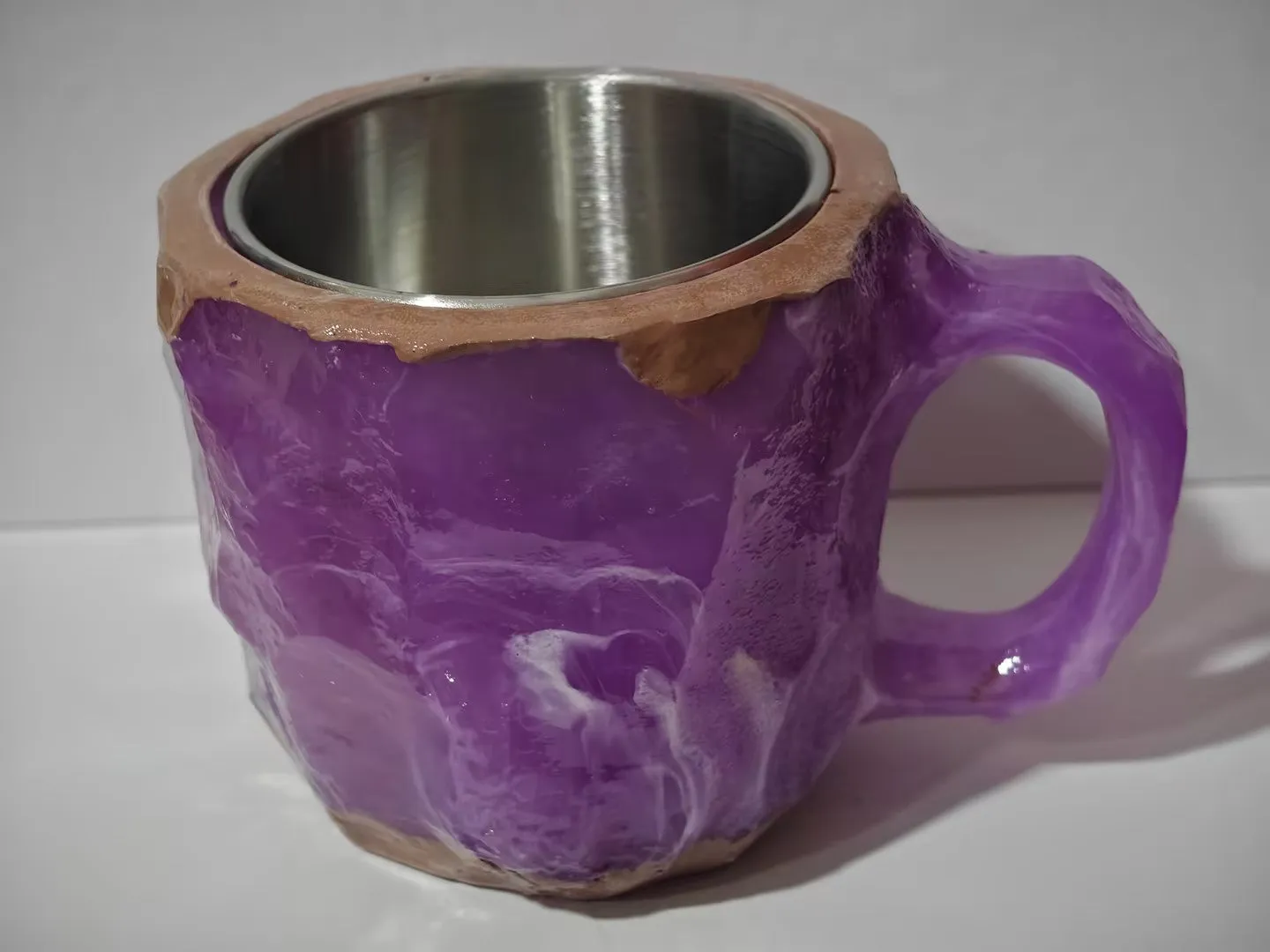 A purple resin coffee mug with a handle, showing a crystal-like structure, on a table.