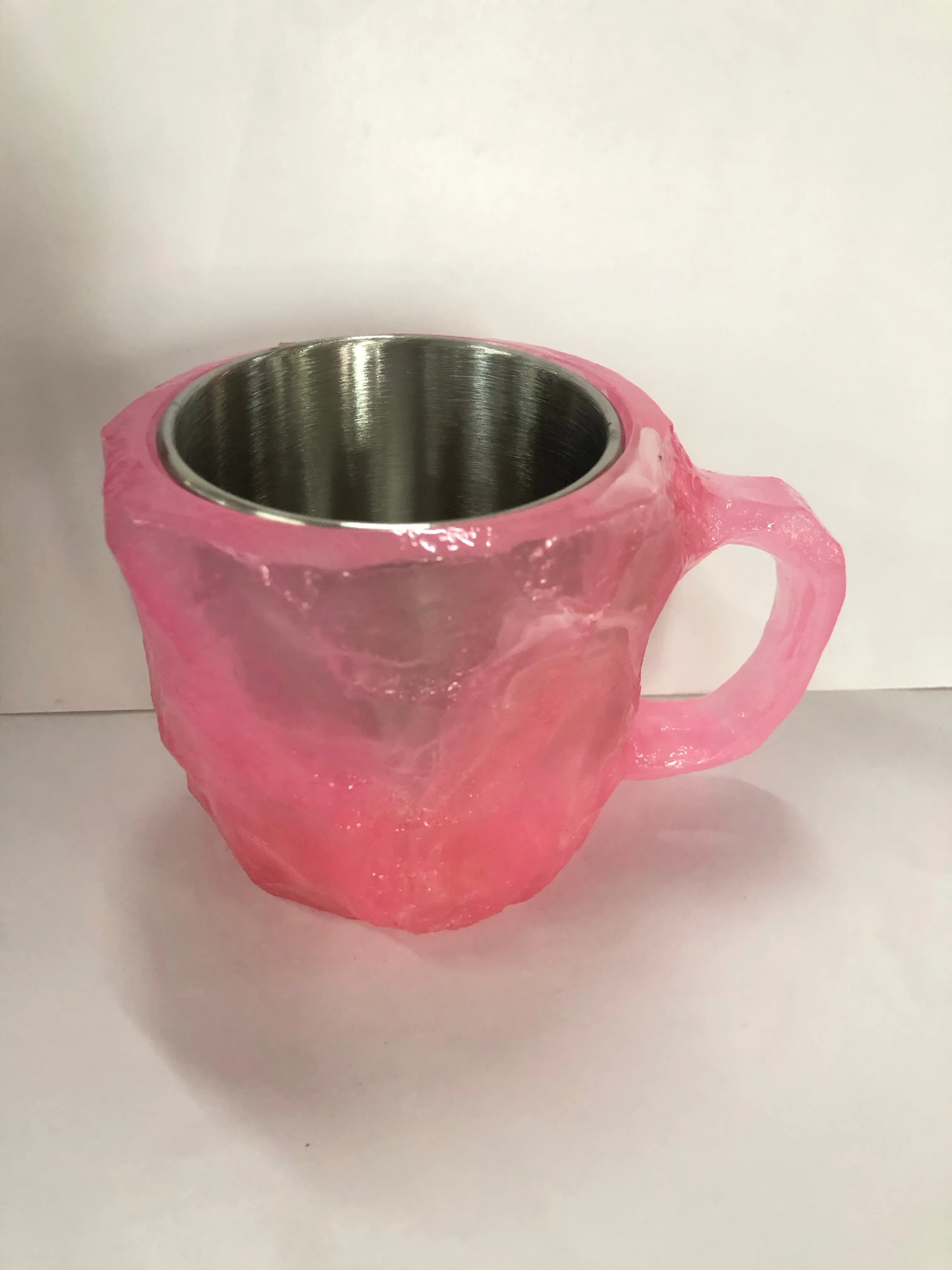 A purple resin coffee mug with a handle, showing a crystal-like structure, on a table.