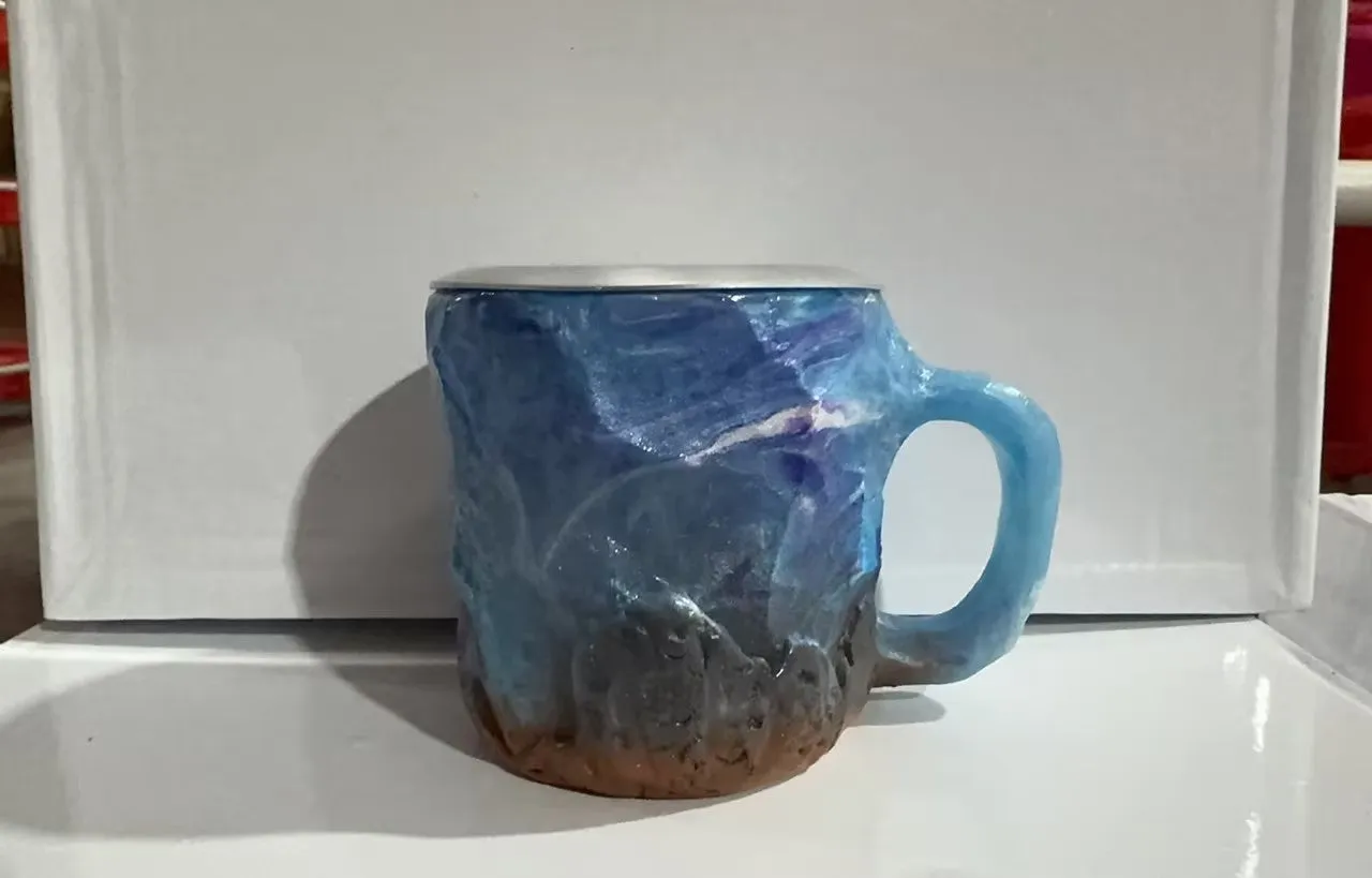 A purple resin coffee mug with a handle, showing a crystal-like structure, on a table.