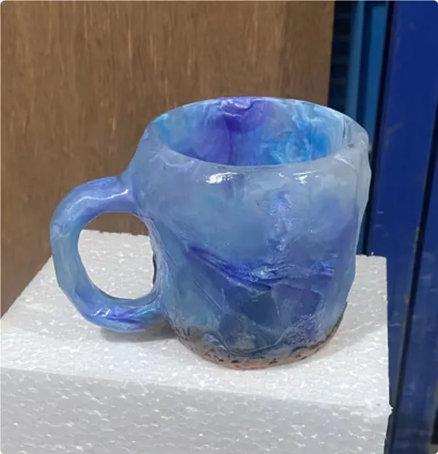 A purple resin coffee mug with a handle, showing a crystal-like structure, on a table.