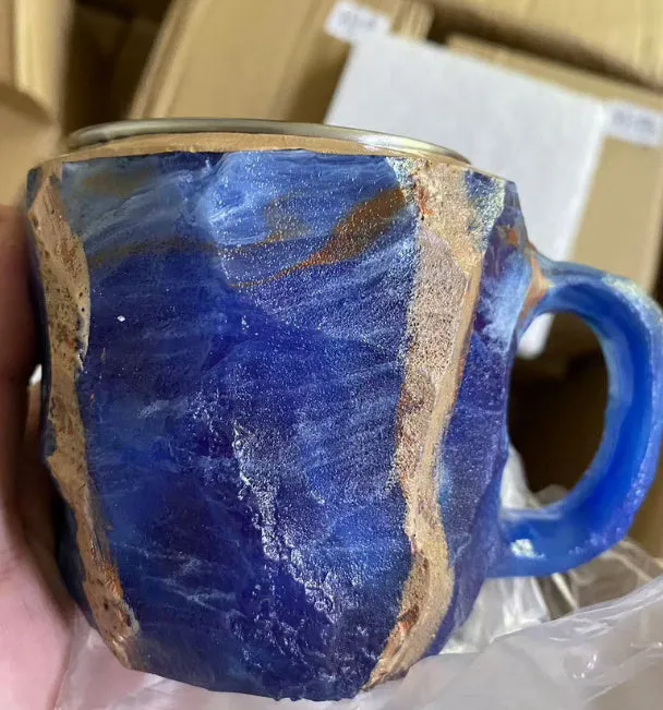 A purple resin coffee mug with a handle, showing a crystal-like structure, on a table.