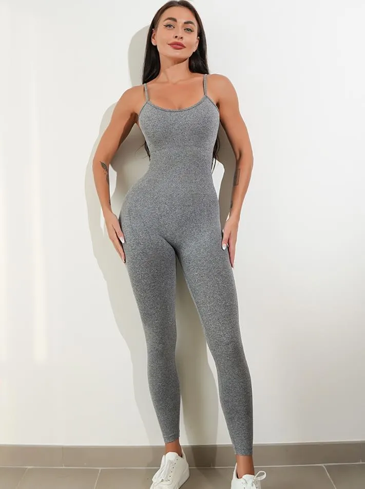 A woman wearing a black sleeveless unitard jumpsuit with spaghetti straps, showing the one-piece design and tummy control panel.