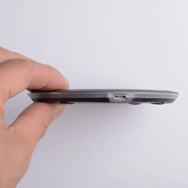 Ultra-thin wireless charger for mobile phone, black, with USB cable, showing charging indicator light