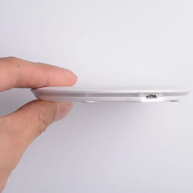 Ultra-thin wireless charger for mobile phone, black, with USB cable, showing charging indicator light