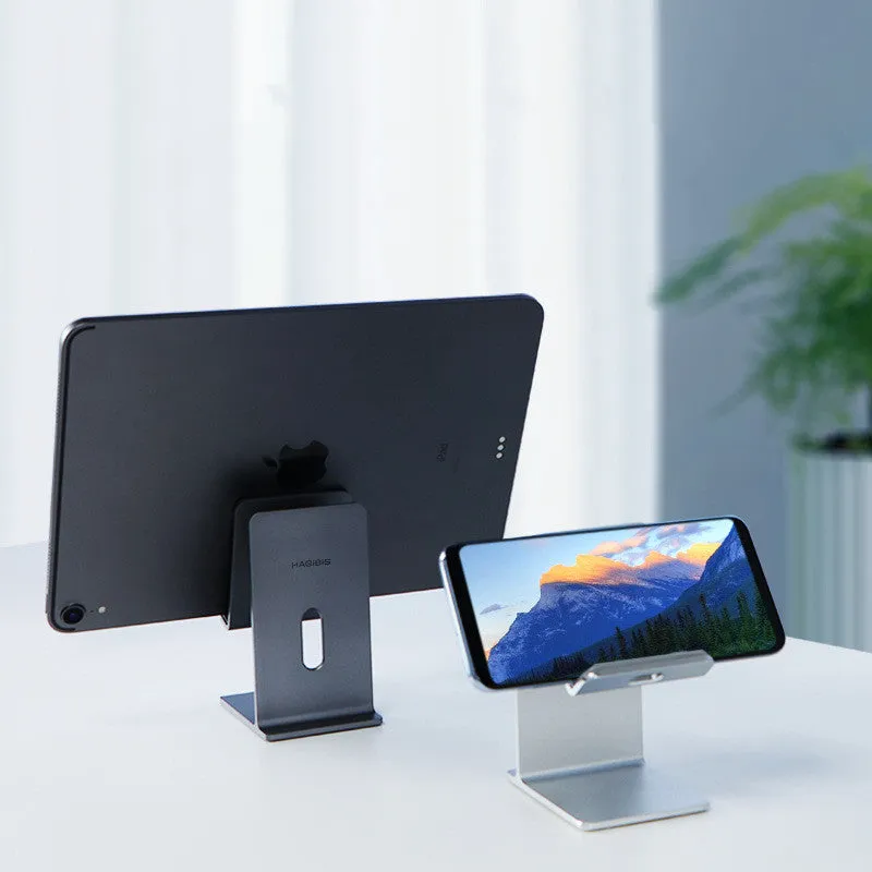 Dark space grey alloy mobile phone and tablet holder on a wooden desktop.