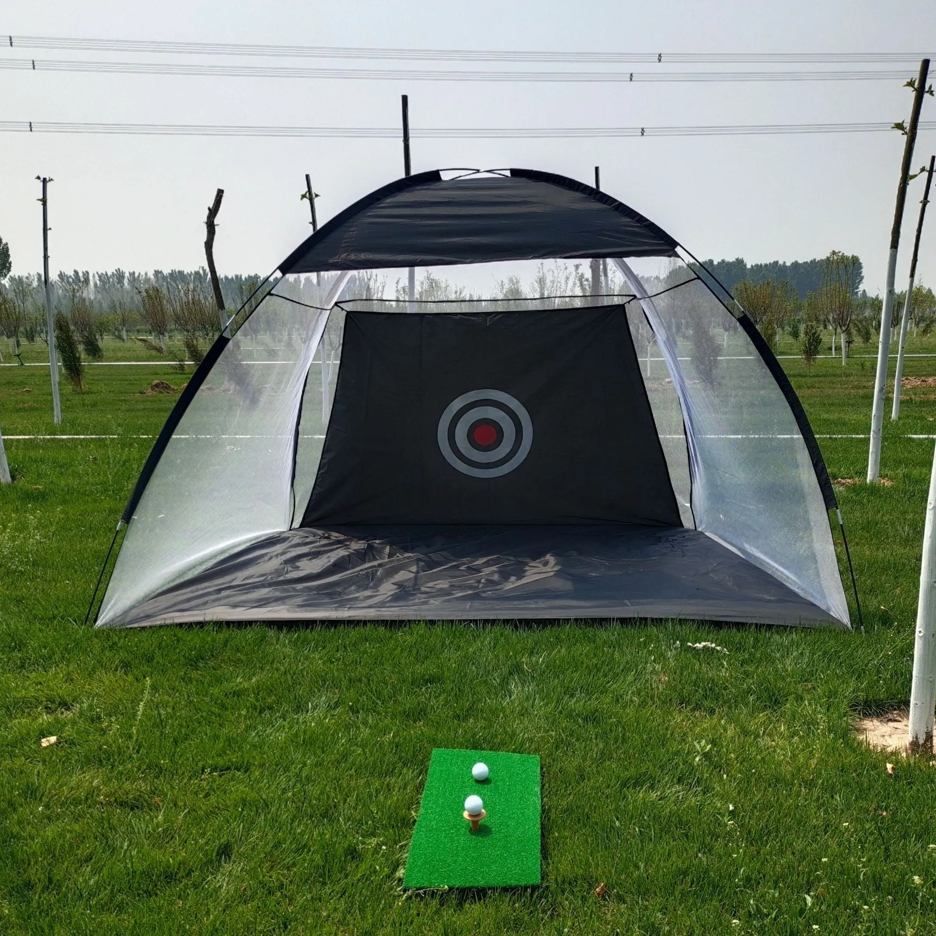 Black and green golf practice net tent set up on grass with fibreglass poles and target sheet
