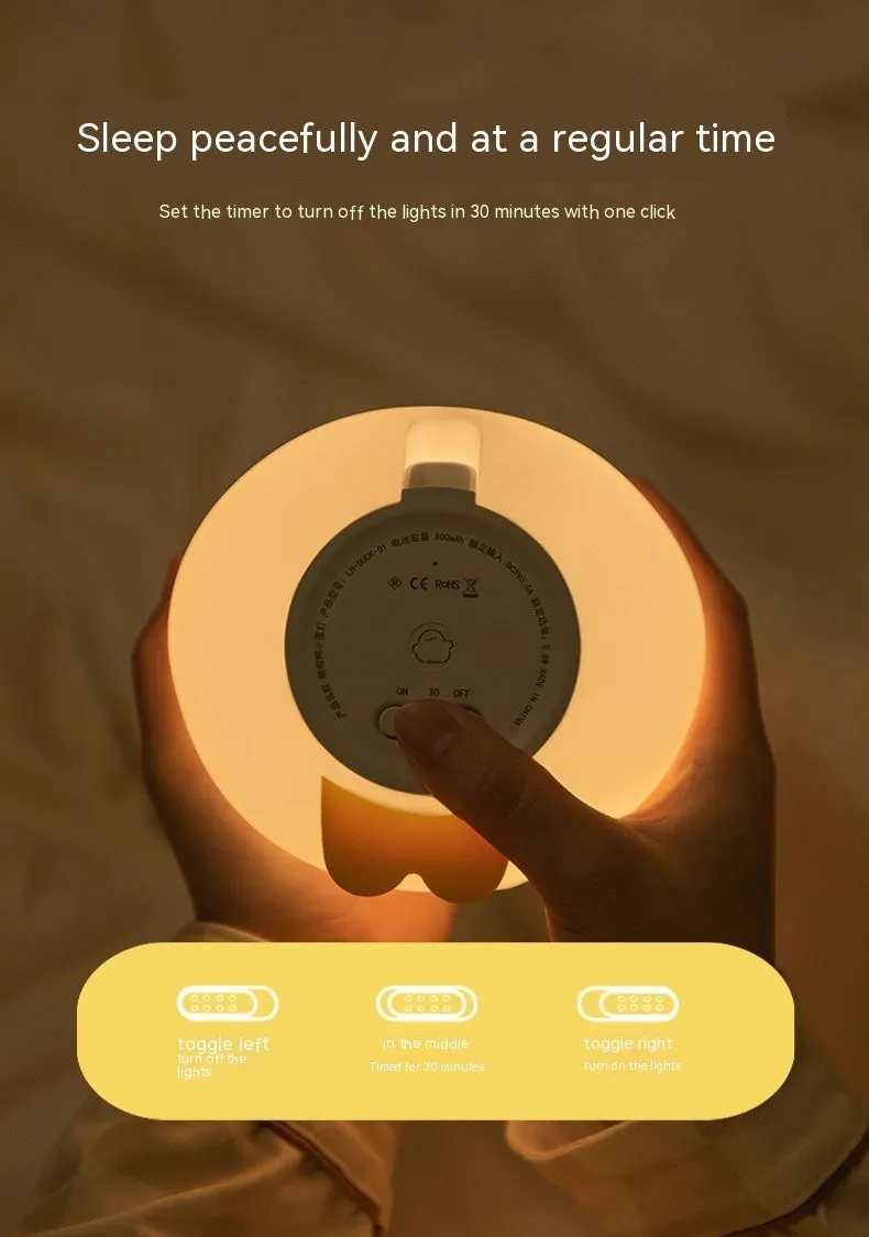 Cute duck shaped LED night lamp with silicone casing and warm light on a bedside table