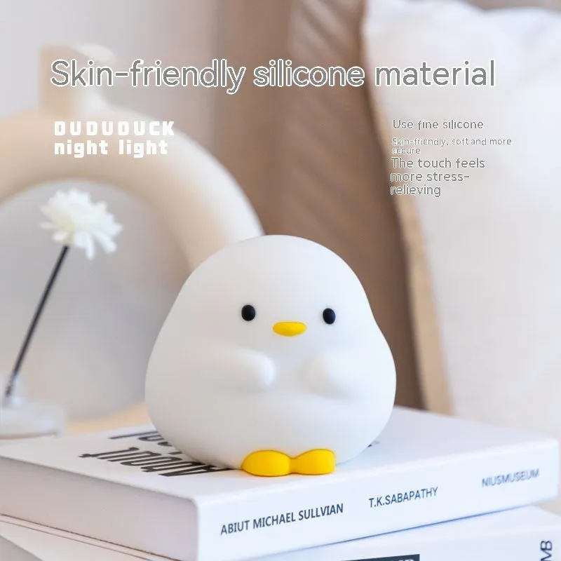 Cute duck shaped LED night lamp with silicone casing and warm light on a bedside table