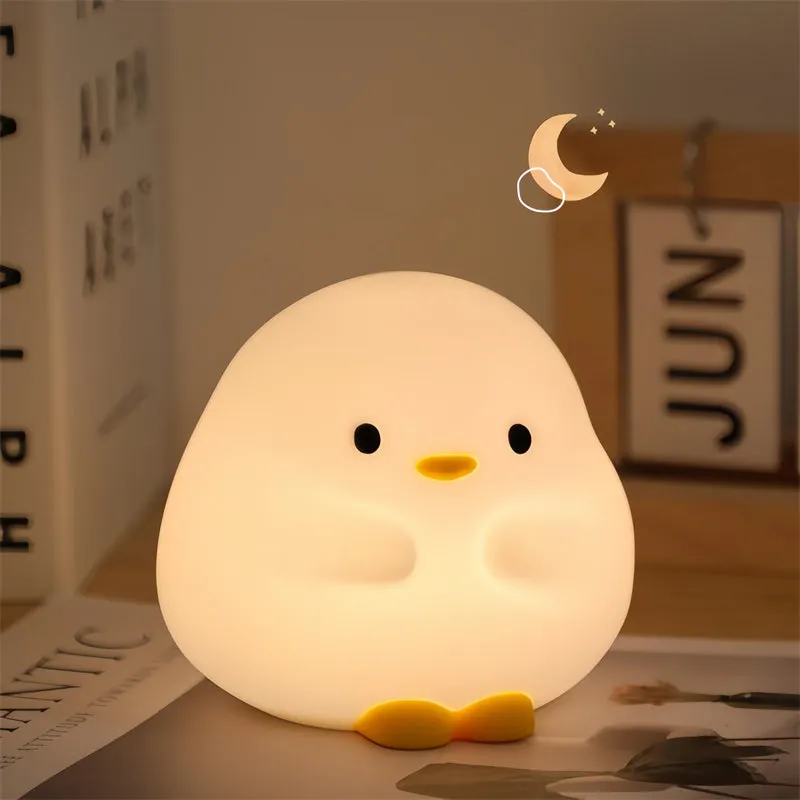 Cute duck shaped LED night lamp with silicone casing and warm light on a bedside table