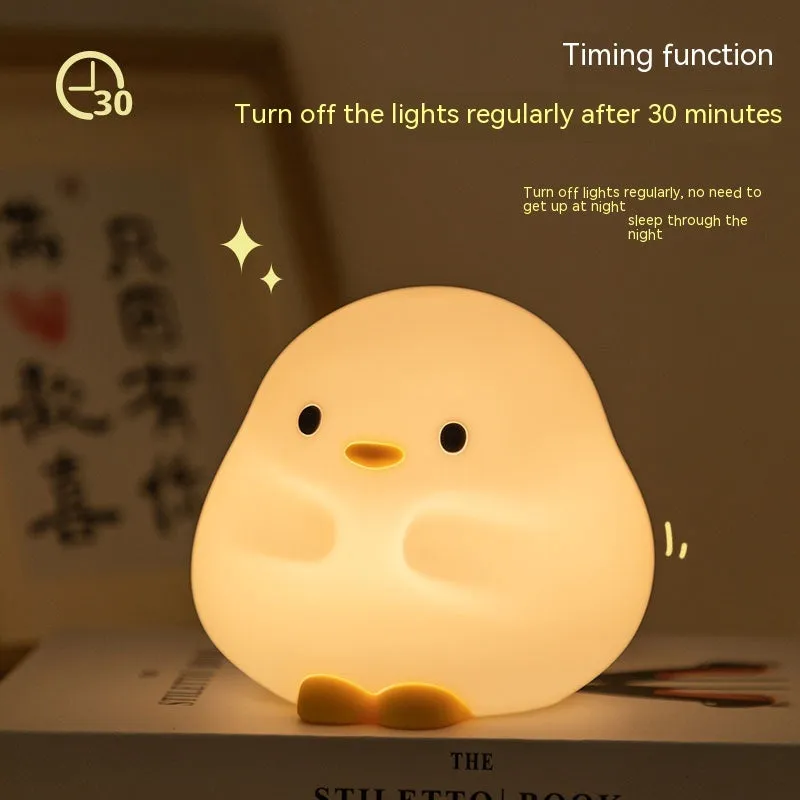 Cute duck shaped LED night lamp with silicone casing and warm light on a bedside table
