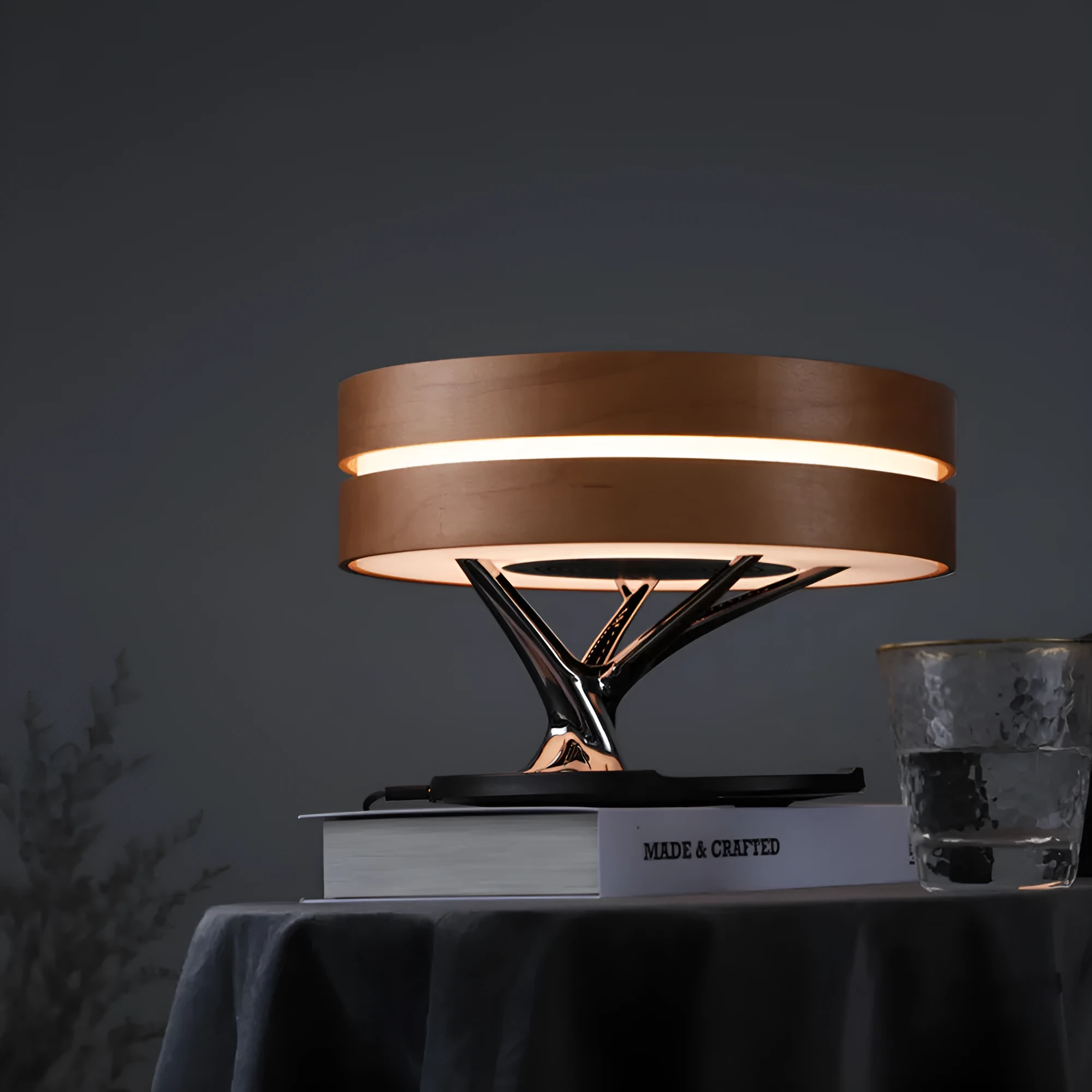 Round maple-coloured ABS PC Bluetooth speaker lamp with LED tree ring and wireless charging pad on a bedside table