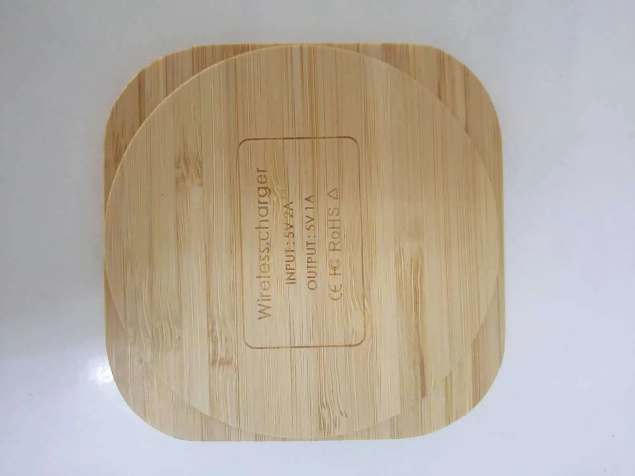 Square bamboo wood 5W wireless charger on a wooden surface.