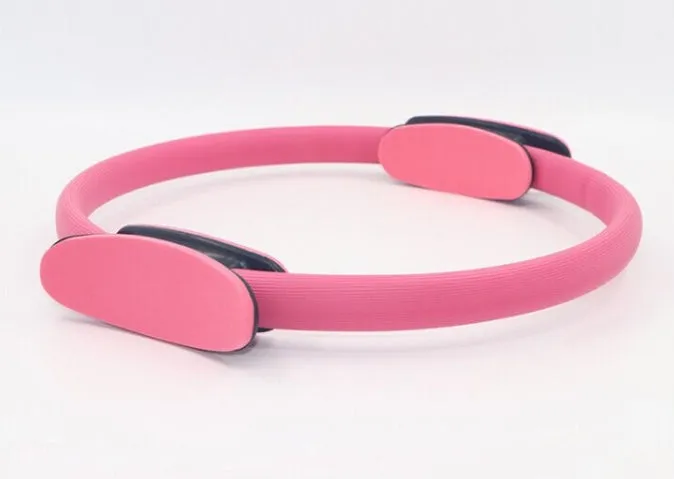 Pink pilates ring with ergonomic design on white background for yoga and home workout resistance training