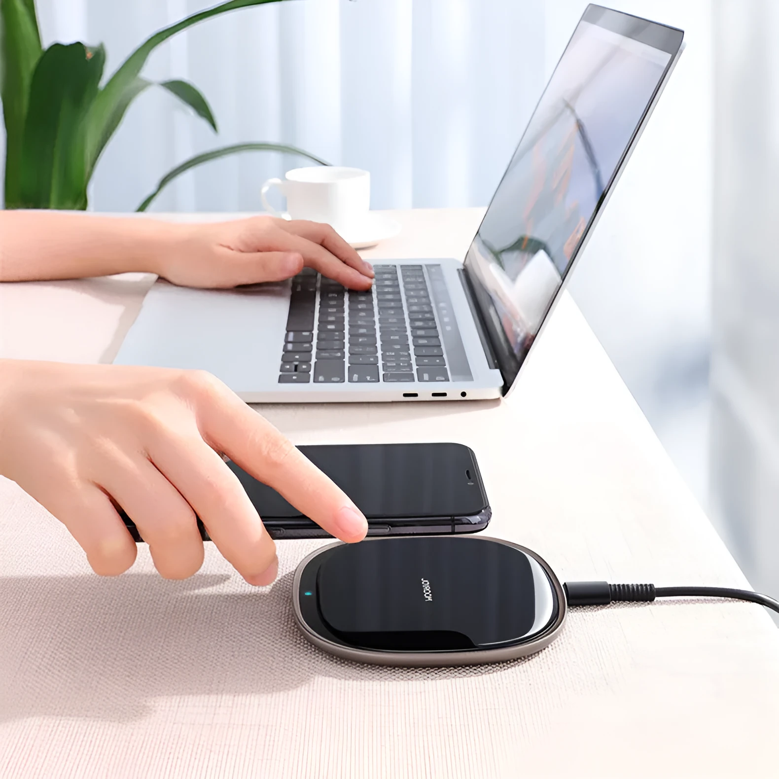 Square black 15W wireless charging pad with glass top and thin zinc alloy frame on a wooden desk
