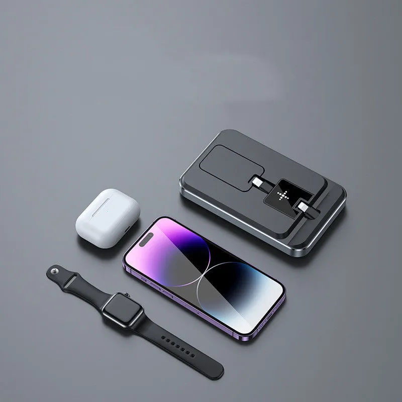Flat folding three in one wireless charger in black with phone, watch, and headphones placed on charging zones
