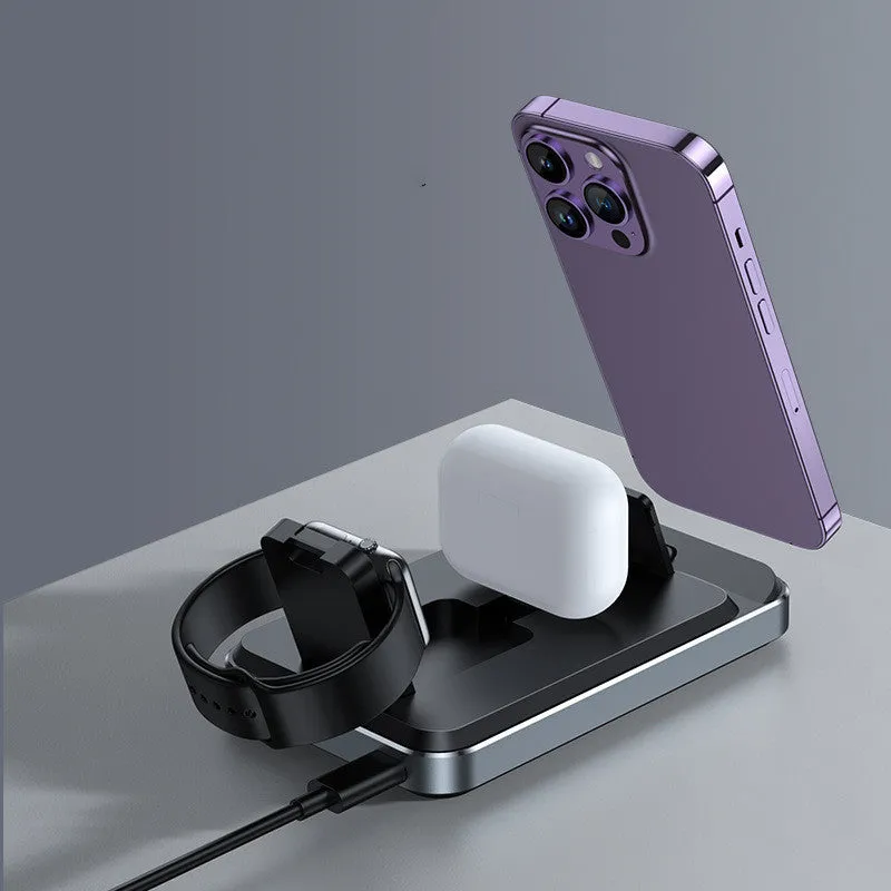 Flat folding three in one wireless charger in black with phone, watch, and headphones placed on charging zones