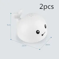White and blue whale bath toy spraying water with LED lights on, floating in a bathtub