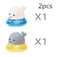 White and blue whale bath toy spraying water with LED lights on, floating in a bathtub