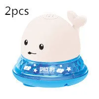 White and blue whale bath toy spraying water with LED lights on, floating in a bathtub
