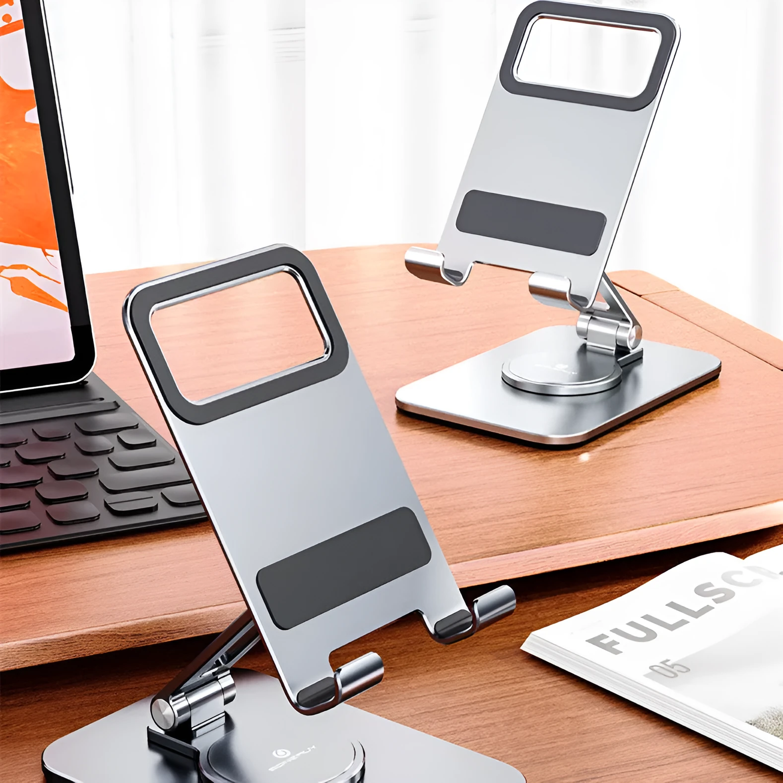 Folding aluminium alloy mobile phone stand in silver on a desktop showing rotary mechanism