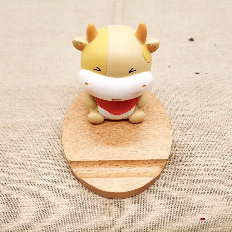 A decorative beech wood and resin mobile phone holder stand featuring themed designs like animals and zodiac signs.