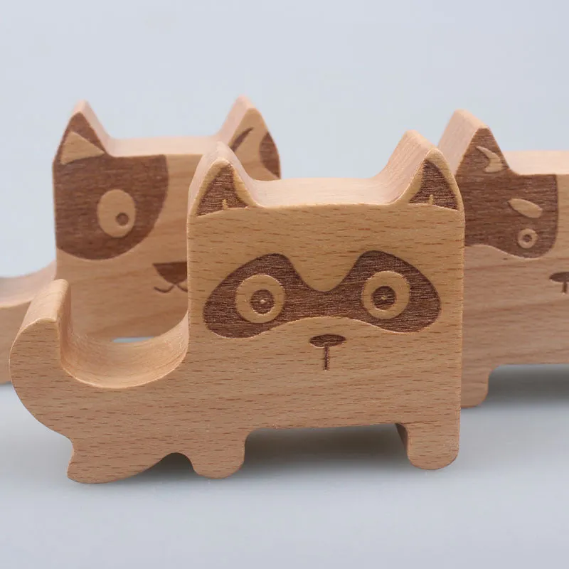 A decorative beech wood and resin mobile phone holder stand featuring themed designs like animals and zodiac signs.