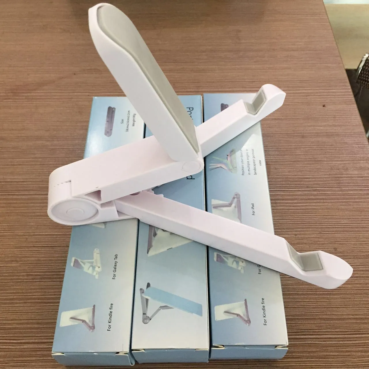 Black foldable tablet holder showing folded size next to tablet for scale