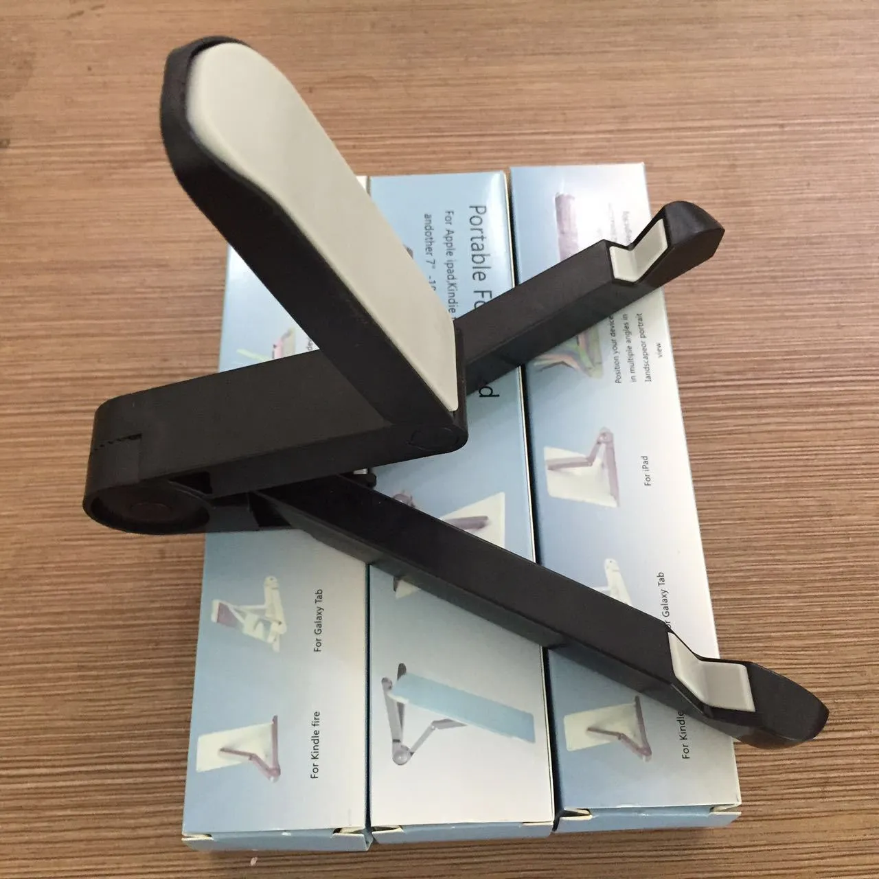 Black foldable tablet holder showing folded size next to tablet for scale