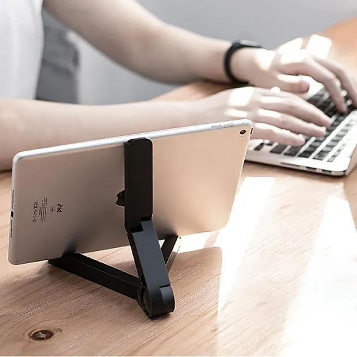 Black foldable tablet holder showing folded size next to tablet for scale