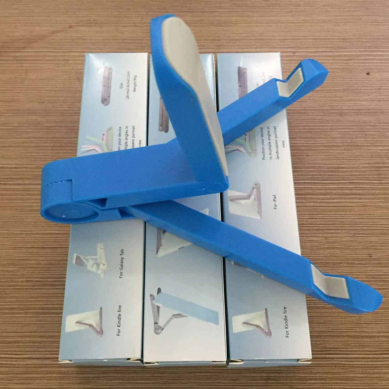 Black foldable tablet holder showing folded size next to tablet for scale