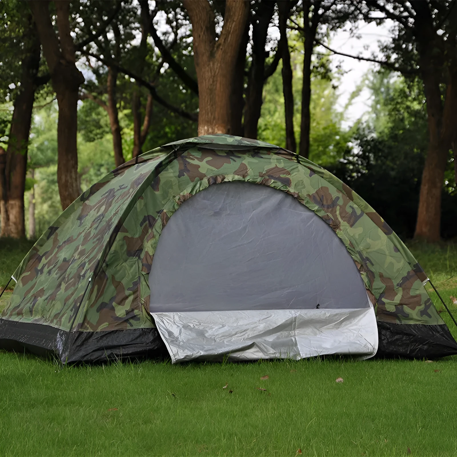 Green camouflage two-person camping tent with triangular skylight and fibre glass poles pitched outdoors.