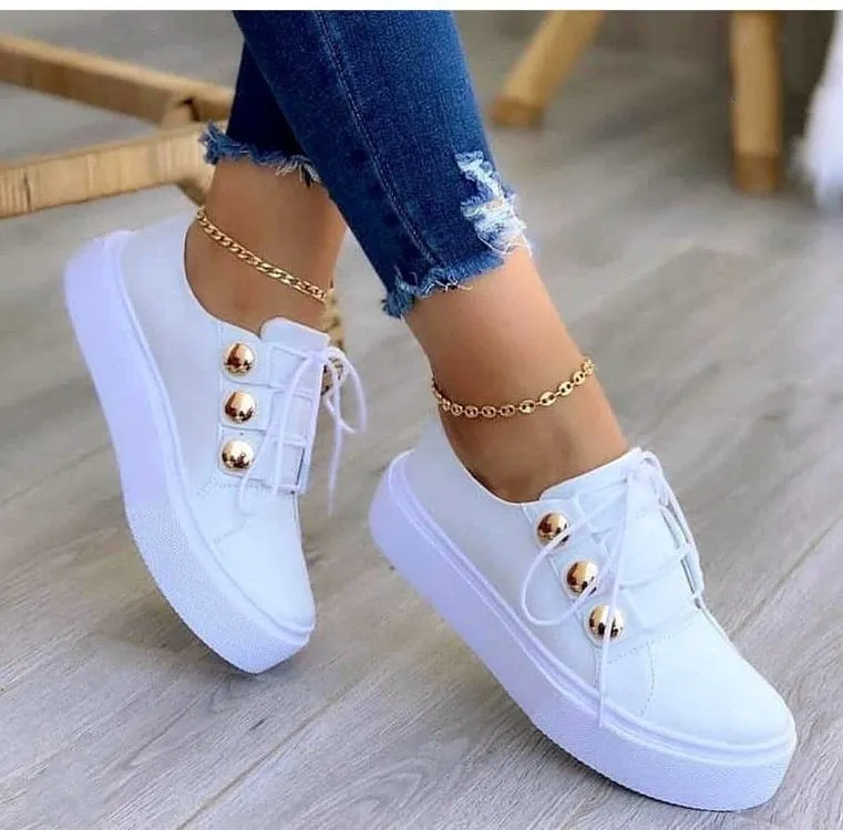 Women's white lace-up flat sneakers with round toe and silver rivet decorative detail.