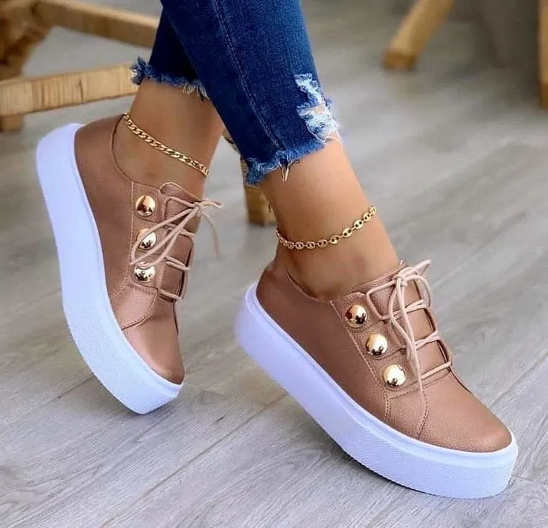 Women's white lace-up flat sneakers with round toe and silver rivet decorative detail.