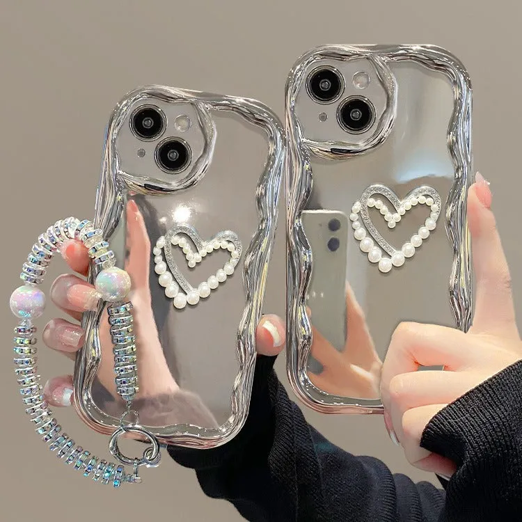 Silver grey silicone phone case for iPhone 15 Pro Max with three-dimensional pearls and chain, electroplated finish, and matching bracelet on a table