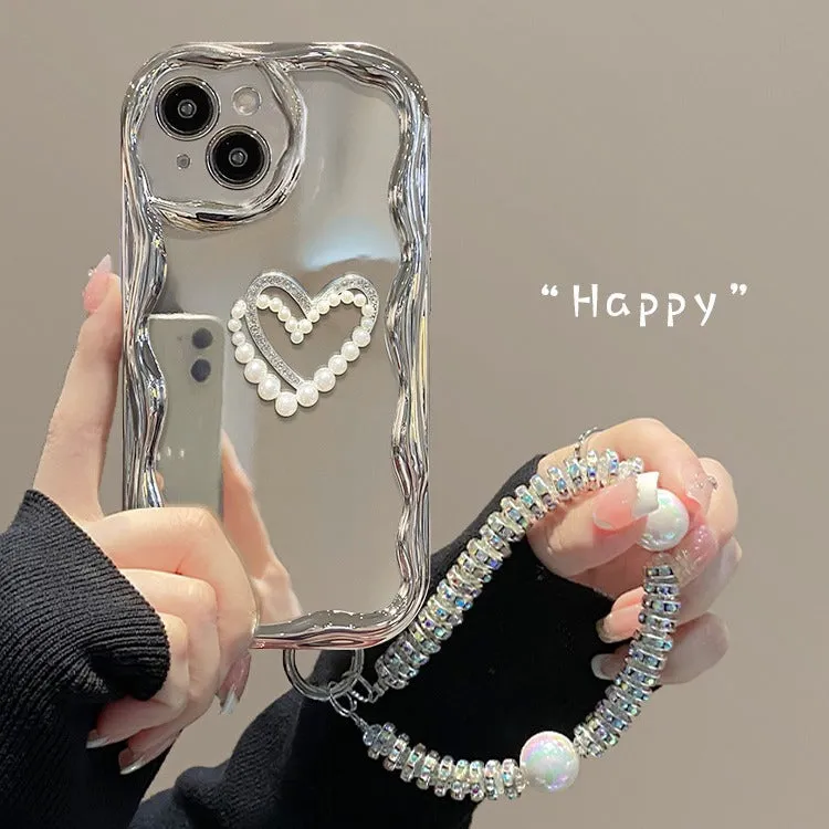 Silver grey silicone phone case for iPhone 15 Pro Max with three-dimensional pearls and chain, electroplated finish, and matching bracelet on a table