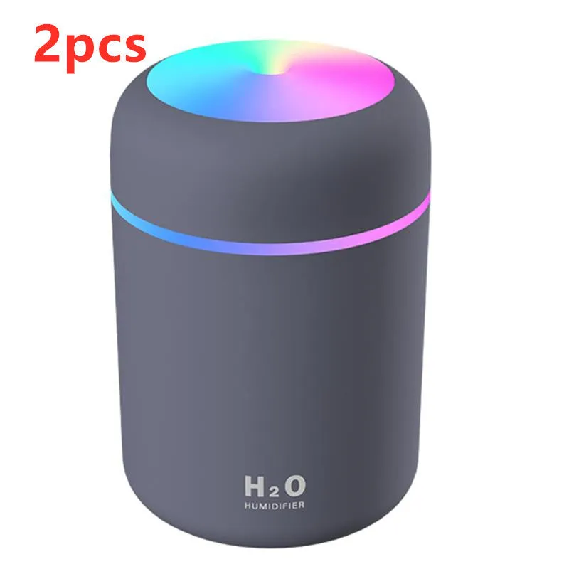 Pink USB desktop humidifier with coloured LED lights and water tank on a wooden desk.