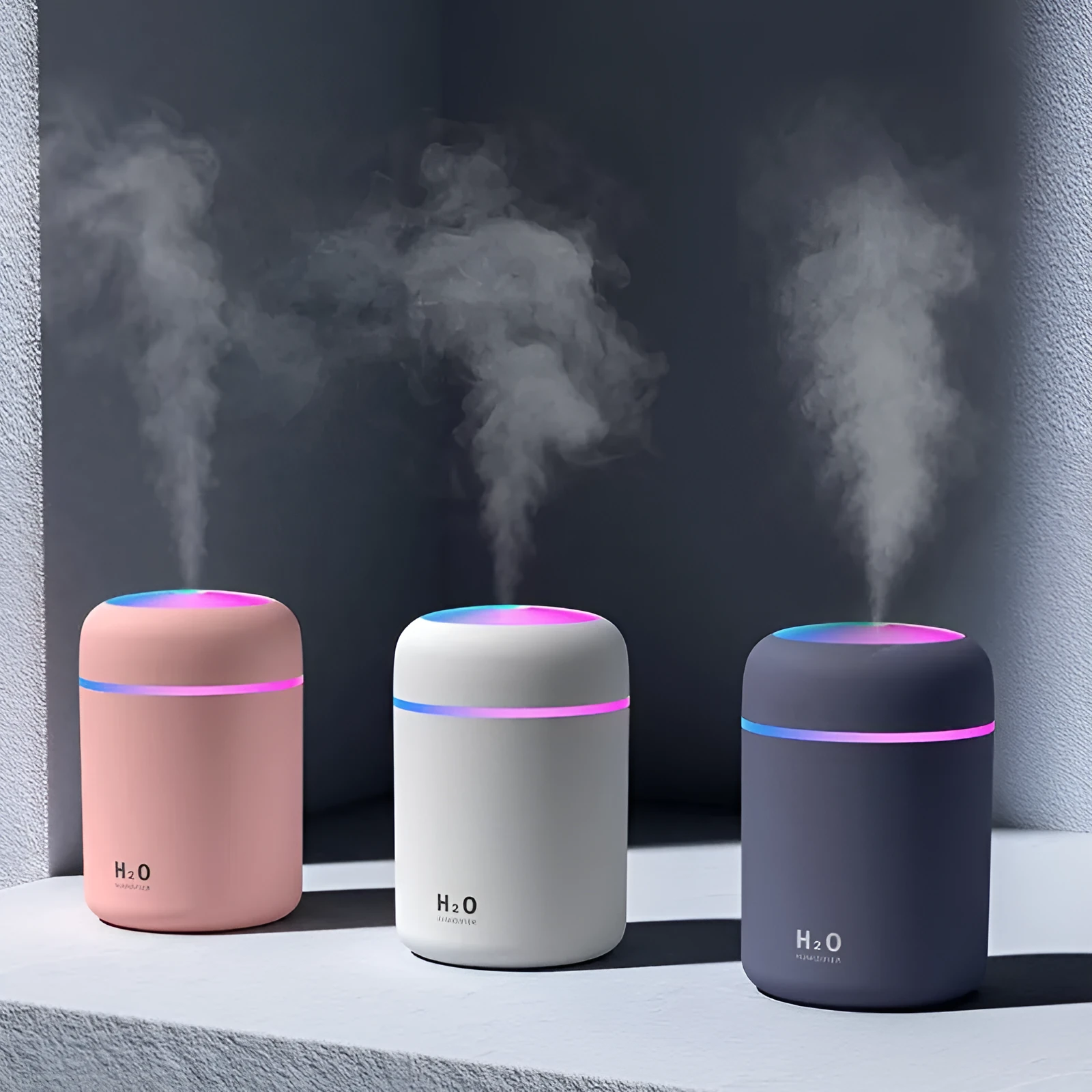 Pink USB desktop humidifier with coloured LED lights and water tank on a wooden desk.