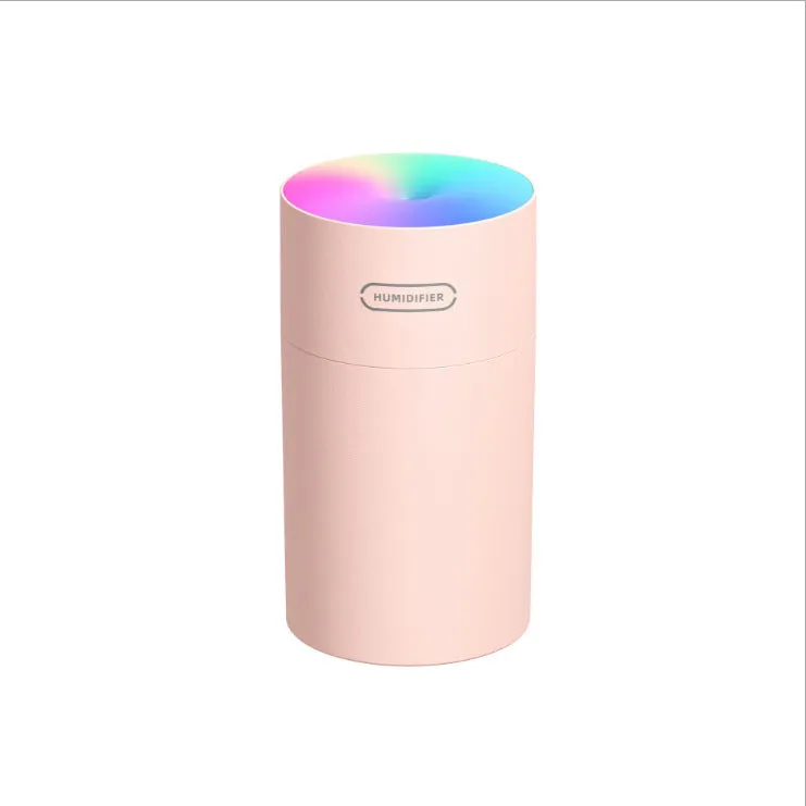 Pink USB desktop humidifier with coloured LED lights and water tank on a wooden desk.