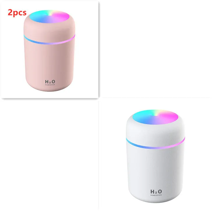 Pink USB desktop humidifier with coloured LED lights and water tank on a wooden desk.