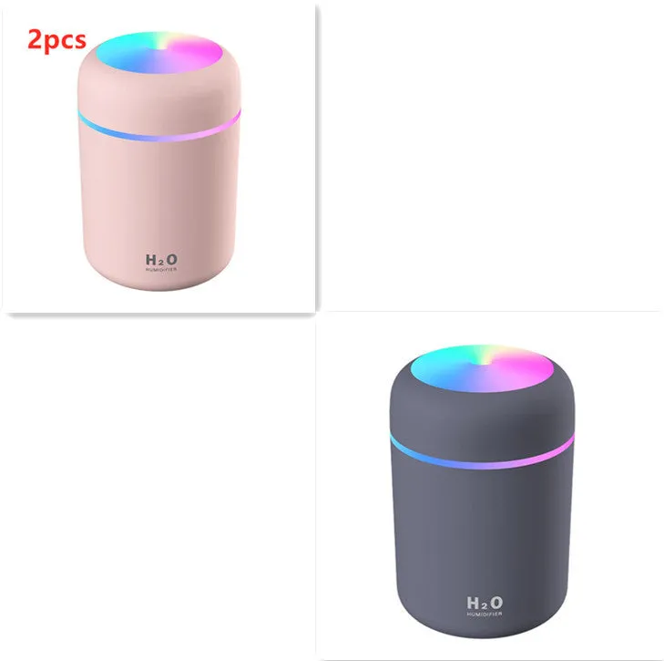 Pink USB desktop humidifier with coloured LED lights and water tank on a wooden desk.
