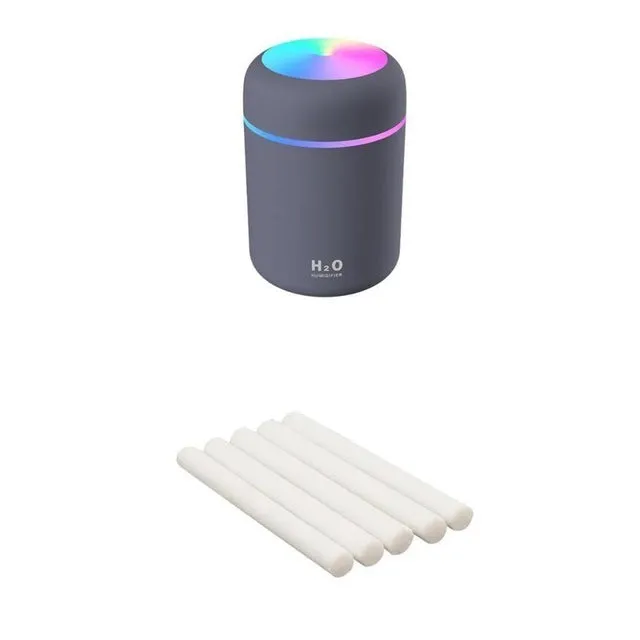 Pink USB desktop humidifier with coloured LED lights and water tank on a wooden desk.