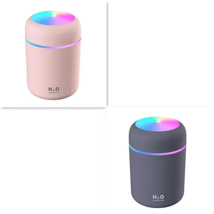 Pink USB desktop humidifier with coloured LED lights and water tank on a wooden desk.