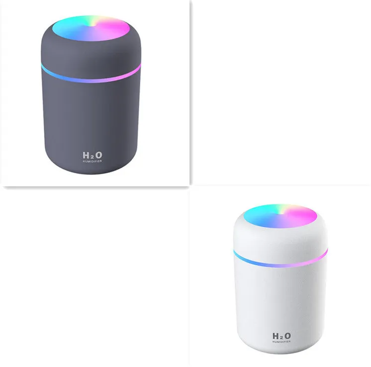 Pink USB desktop humidifier with coloured LED lights and water tank on a wooden desk.
