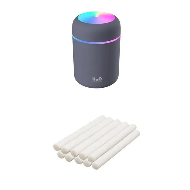 Pink USB desktop humidifier with coloured LED lights and water tank on a wooden desk.